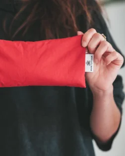 Red cotton eye pillow with flax seeds and lavender, gentle weight for relaxation.