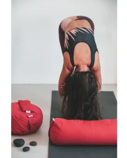 Yoga bolster rosso con pula di grano saraceno e fodera in cotone, rullo cilindrico per pratica restaurativa.