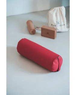 Yoga bolster rosso con pula di grano saraceno e fodera in cotone, rullo cilindrico per pratica restaurativa.