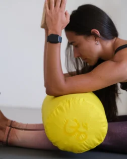 Yoga bolster giallo con pula di grano saraceno e fodera in cotone, supporto cilindrico per pratica restaurativa.