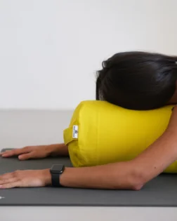 Yoga bolster giallo con pula di grano saraceno e fodera in cotone, supporto cilindrico per pratica restaurativa.