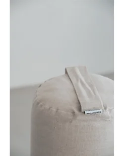 Natural linen yoga bolster with buckwheat hulls, cylindrical support for restorative yoga and pranayama.