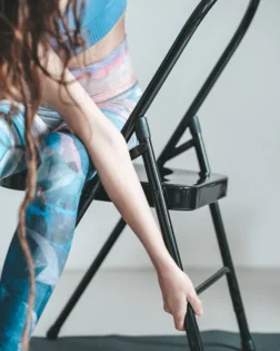 Black backless metal yoga chair with support bar and folding frame.