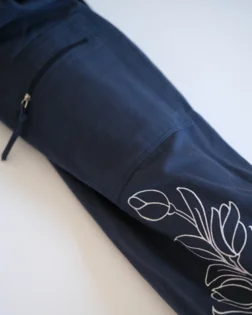 Sacca in cotone blu scuro con motivo Gardenia bianco, tasca con cerniera e tracolla regolabile.